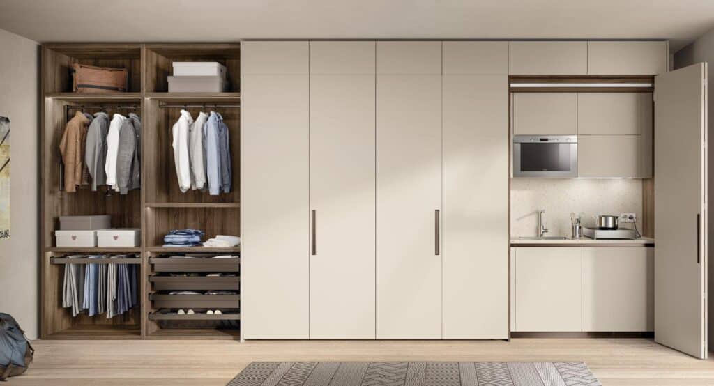 Modern closet with open wardrobe and integrated kitchenette, featuring clothes, shelves, and kitchen appliances.