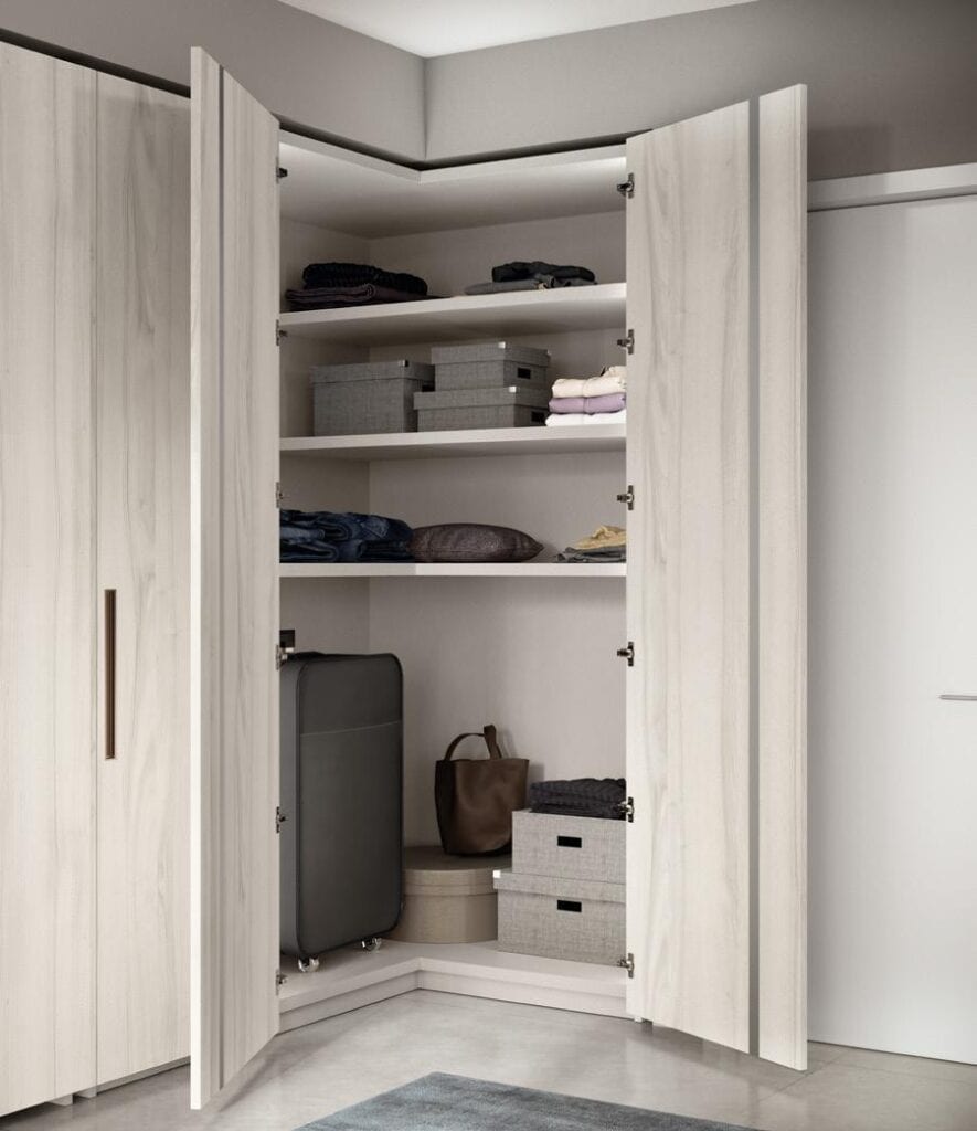 Open wardrobe with shelves containing folded clothes, storage boxes, a suitcase, and a bag.