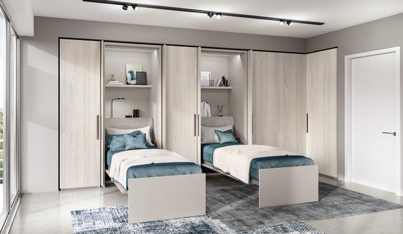 Modern bedroom with two fold-out beds from a wall unit, blue bedding, gray walls, and a large rug.