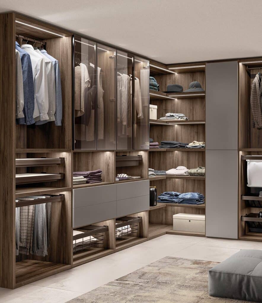Modern walk-in closet with wooden shelves, glass doors, hanging clothes, folded garments, and storage boxes.