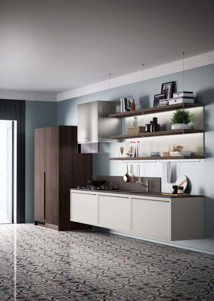 Modern kitchen with blue walls, brown cabinets, patterned floor tiles, open shelves displaying decor and plants, and a stovetop with hanging utensils.