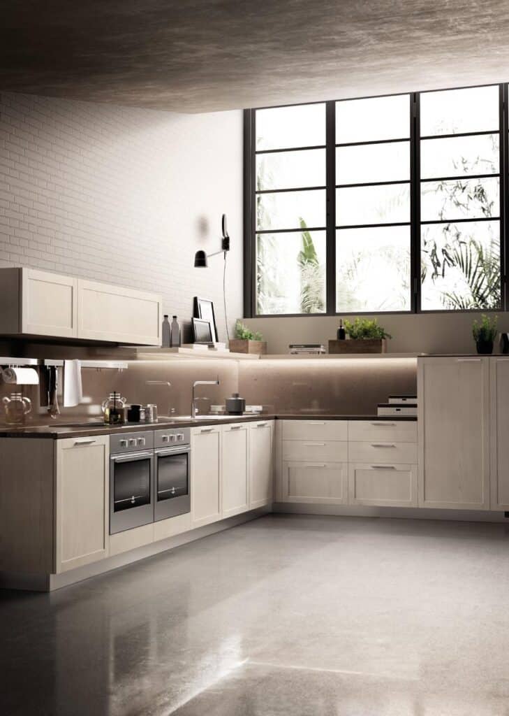 Modern kitchen with light wood cabinets, stainless steel appliances, large windows, and potted plants on the countertop.