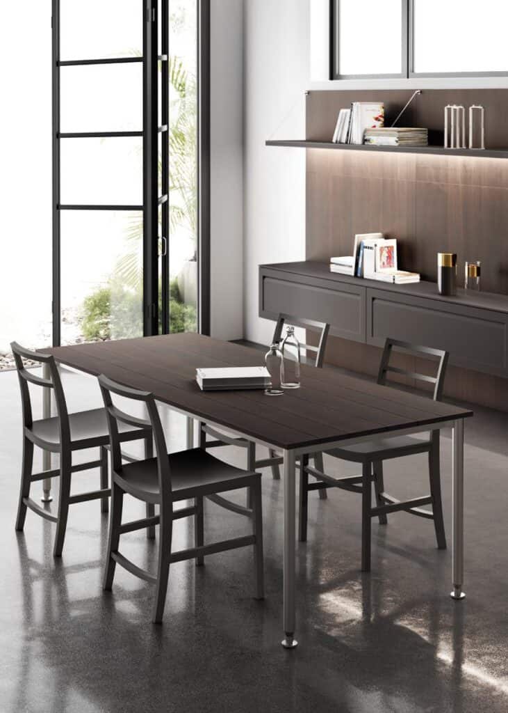 Modern dining area with a dark wooden table, four matching chairs, a sideboard, and a glass door opening to greenery.
