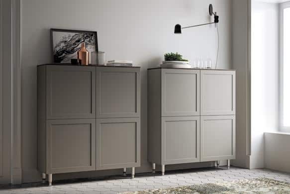 Two gray cabinets with decorative items on top, under a wall-mounted black lamp, on a light-colored floor in a minimalist room.