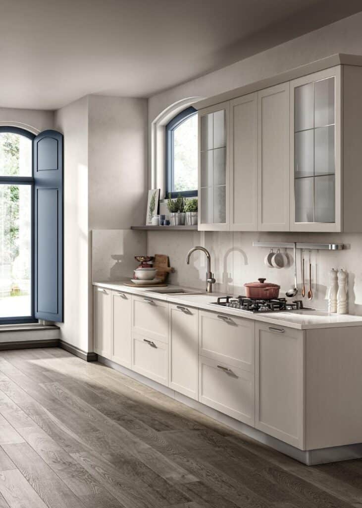 Modern kitchen with cream cabinets, a gas stove, and large windows with blue shutters.