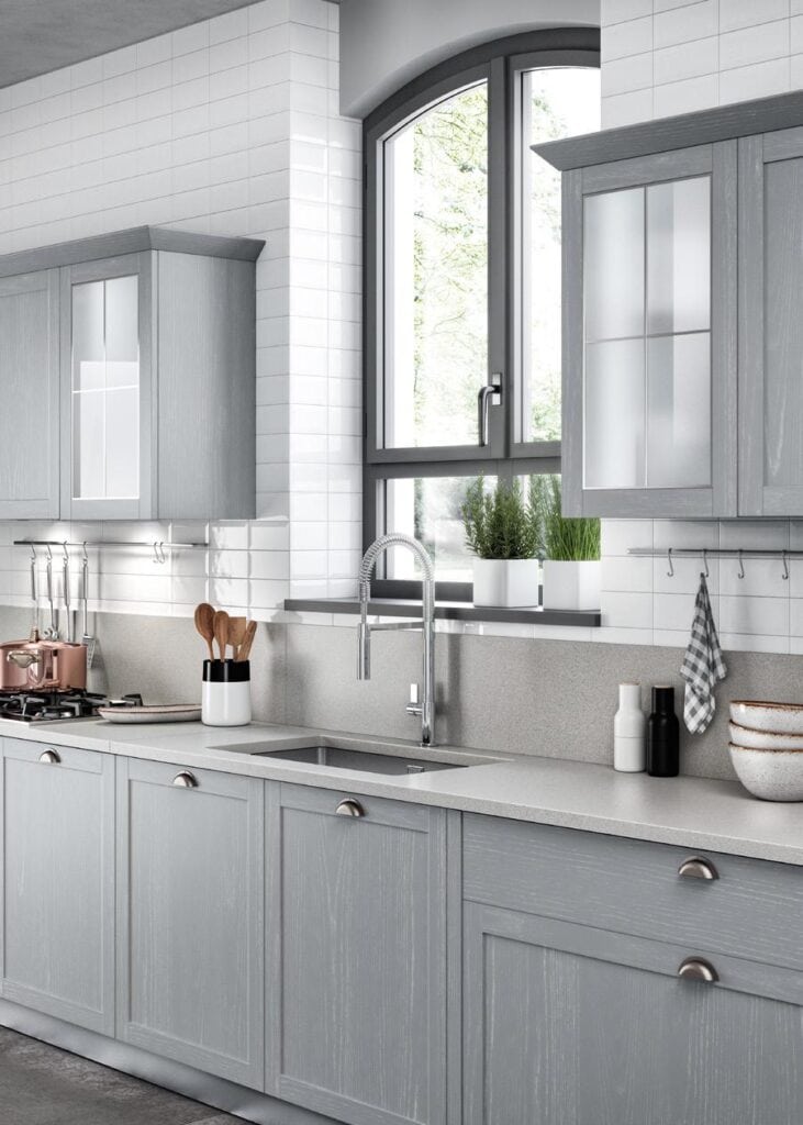 Modern kitchen with light gray cabinets, a stainless steel sink, and a large arched window.