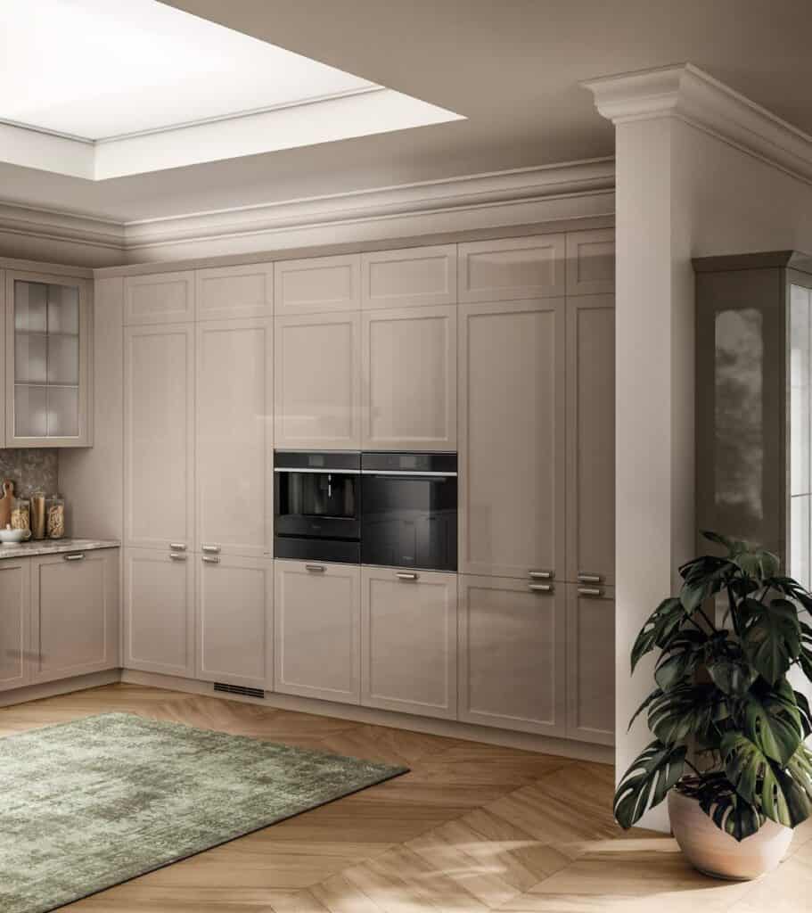 Modern kitchen with beige cabinetry, built-in appliances, a green rug, and a potted plant.