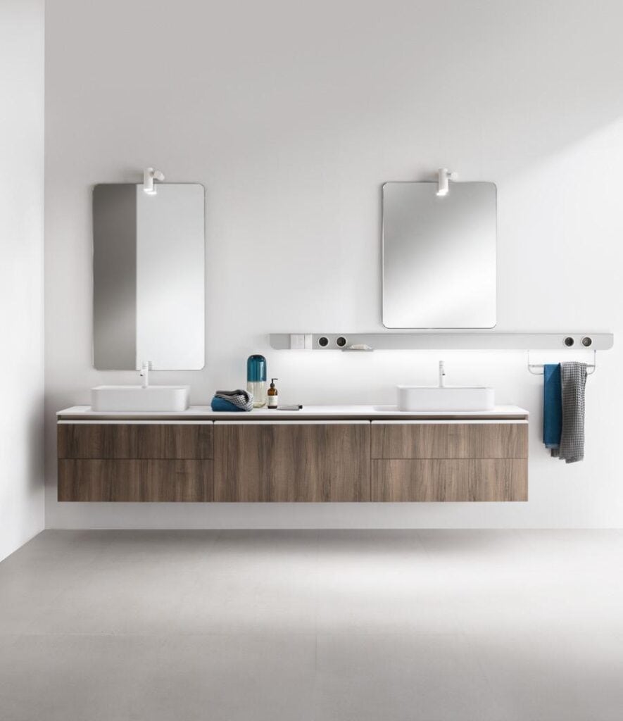 Modern bathroom interior with two sinks, mirrors, and wooden cabinetry.