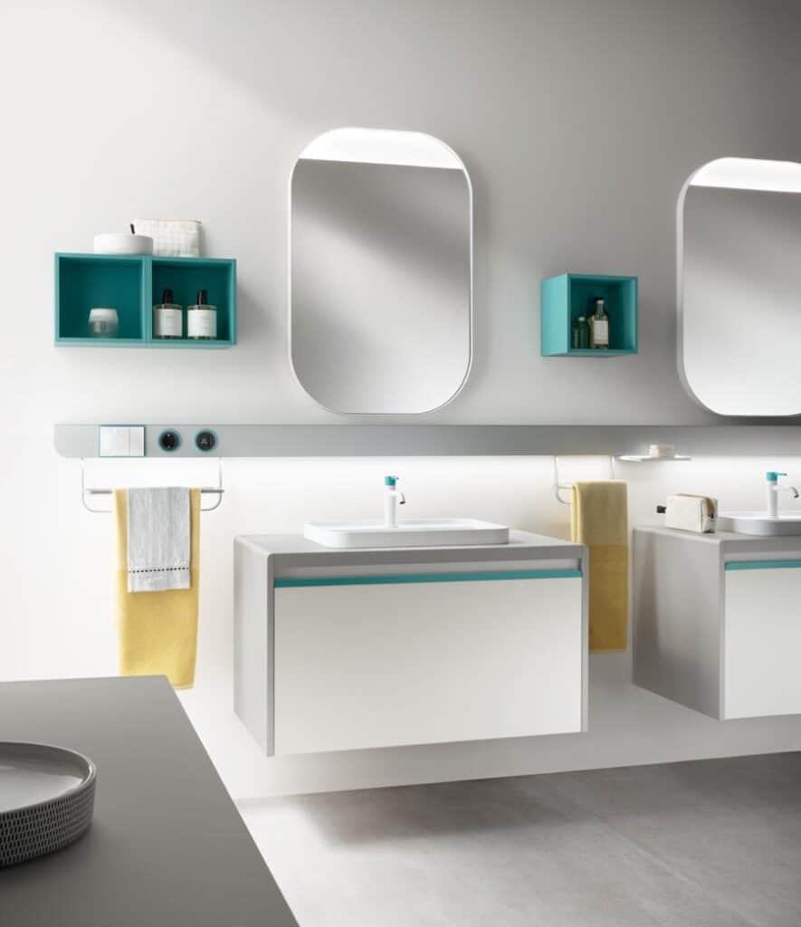 Modern bathroom with two rectangular mirrors, floating vanities, teal shelves, and towel racks holding yellow towels.