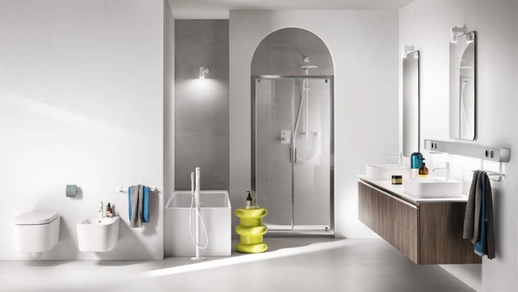 Modern bathroom with a wall-mounted toilet and bidet, a shower with sliding glass doors, a rectangular bathtub, dual sinks with vanity and mirrors, and a yellow stackable side table.