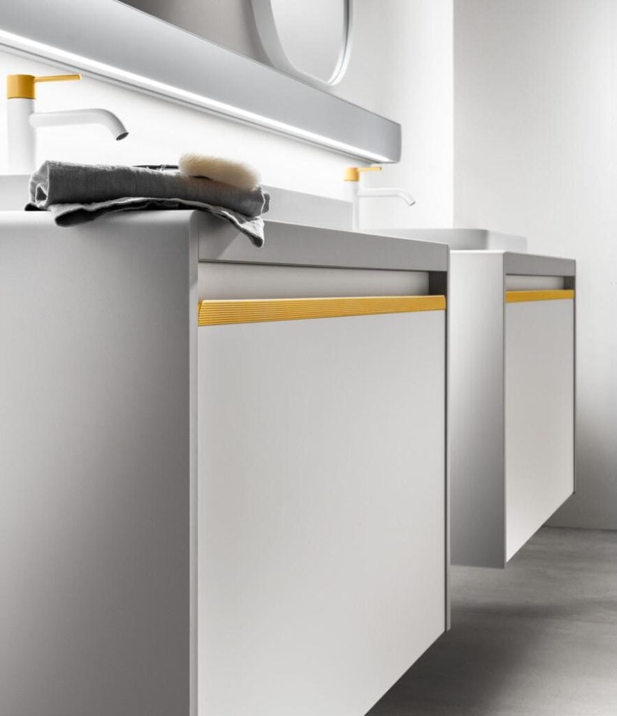 Modern bathroom vanity with white cabinets, yellow accents, and a countertop featuring a sink and faucets.