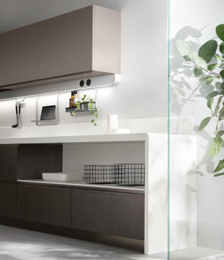 Modern kitchen with a minimalist design, featuring a white countertop, dark lower cabinets, upper cabinets, and plants for decoration.