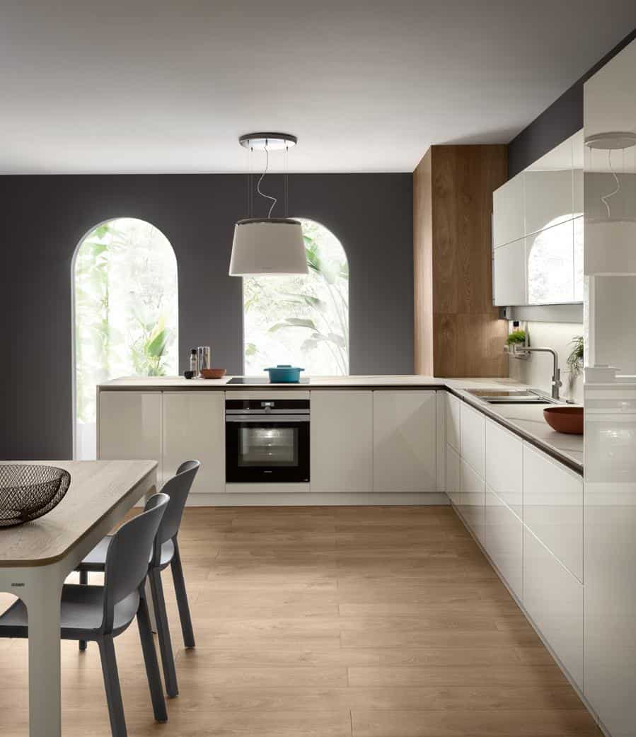 Modern kitchen with white cabinets, wood flooring, a dining table with chairs, and a large ceiling light fixture.