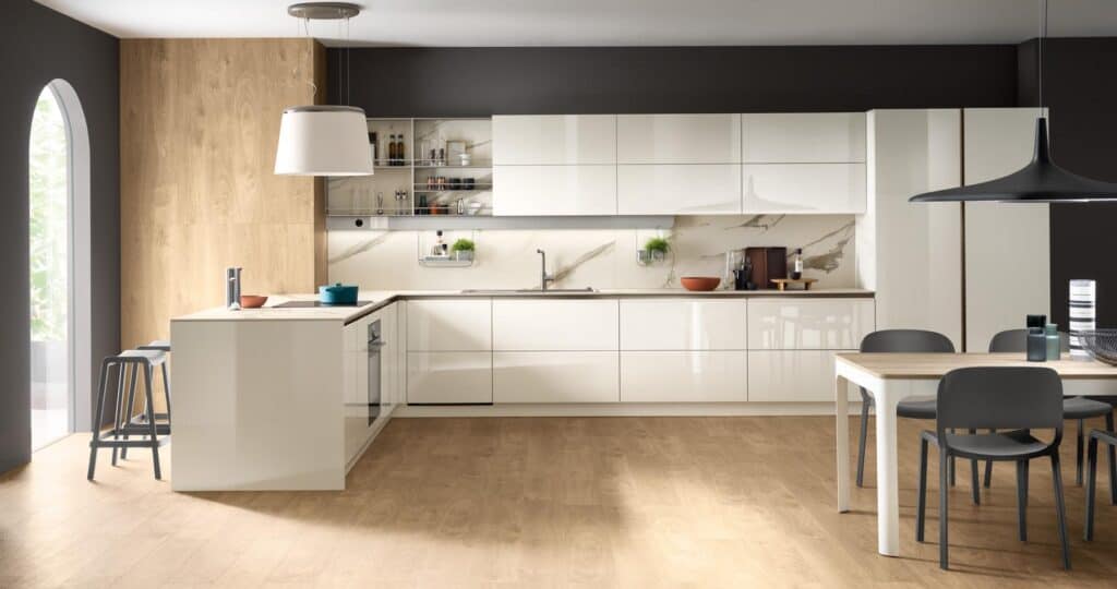Modern kitchen with white cabinets, wood accents, an island with bar stools, and a dining table with black chairs.