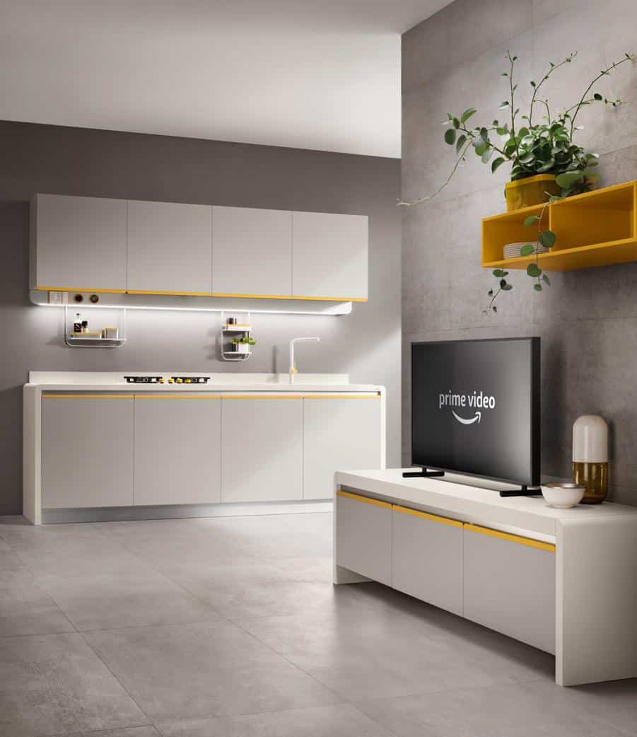 Modern kitchen interior with sleek cabinets, a mounted TV displaying "Prime Video," and a yellow accent shelf with a plant.