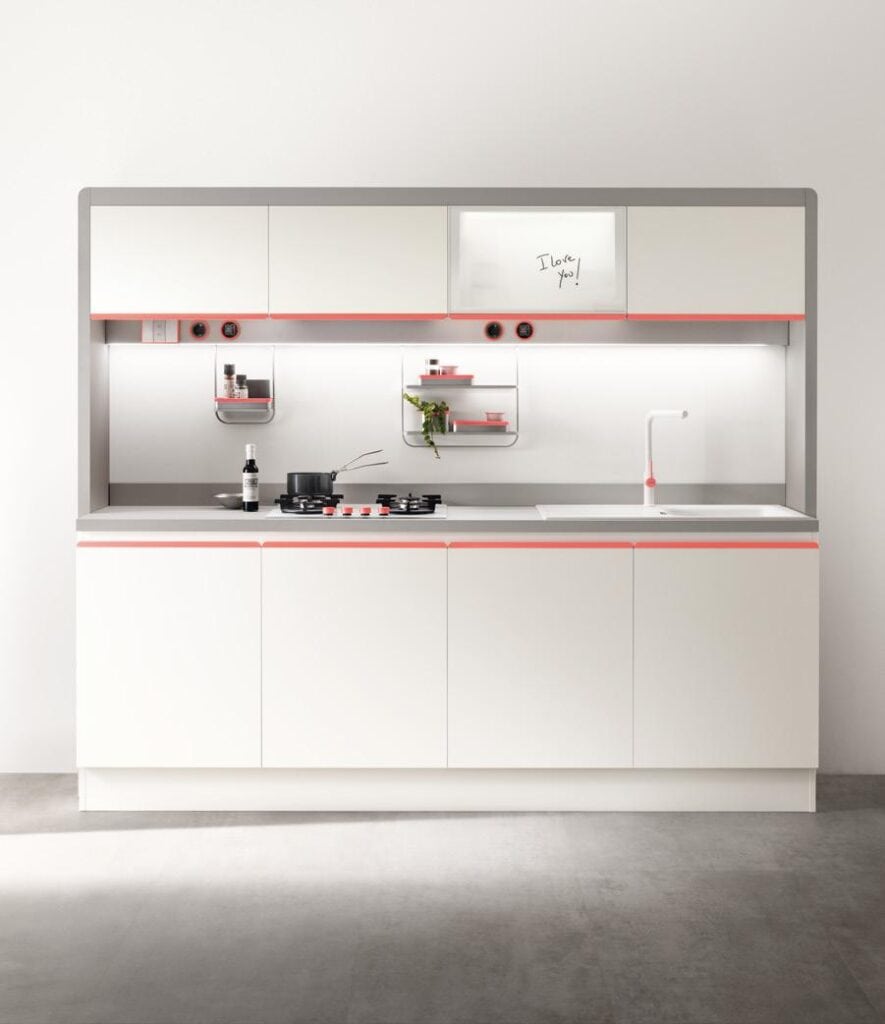 Modern kitchen with white cabinets, pink accents, stovetop, sink, and shelves.