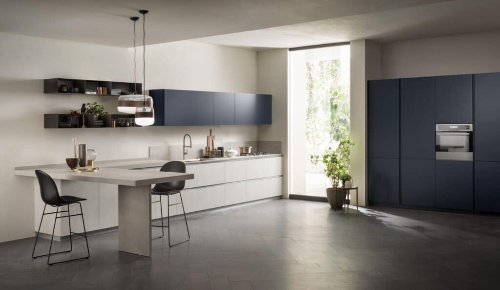 Modern kitchen with minimalist design, featuring dark cabinetry, a built-in oven, a large island with bar stools, pendant lights, and a tall window.