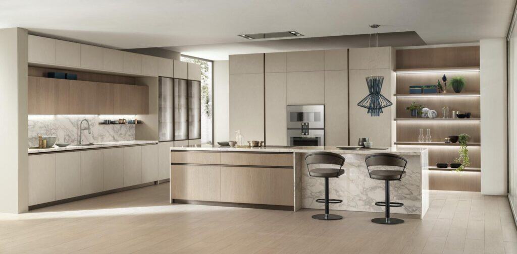 Modern kitchen with light wood cabinets, marble countertops, an island with barstools, and open shelving decorated with plants and dishes.