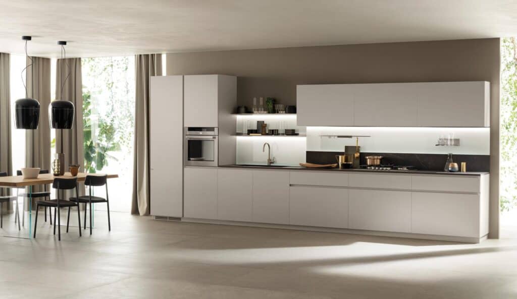 Modern kitchen with white cabinets, a built-in oven, and a dining table featuring two black pendant lights.