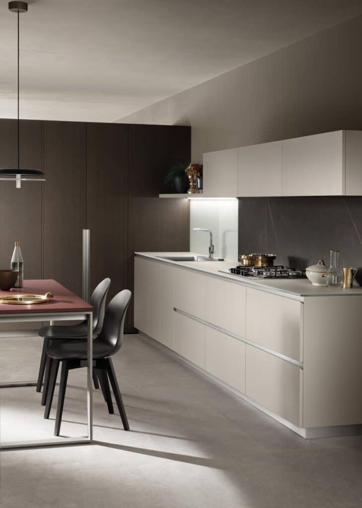 Modern kitchen with sleek cabinets, a gas stovetop, and a dining table with black chairs.