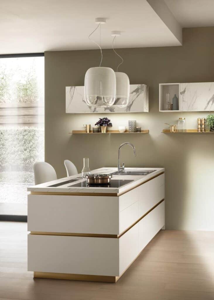 Modern kitchen with a sleek white island, built-in stovetop, and overhead pendant lights; minimalist decor with marble accents.
