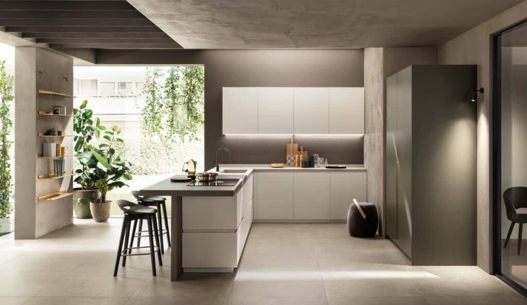 Modern kitchen with minimalist design, featuring white cabinets, a large island with bar stools, and potted plants near a large window.
