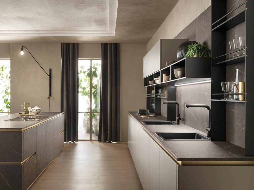 Modern kitchen with dark marble countertops, open shelving, dark cabinets, a double sink, large windows with dark curtains, and potted plants outside.