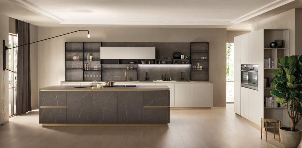 Modern kitchen interior with dark stone countertops, sleek cabinetry, built-in ovens, and a large potted plant.