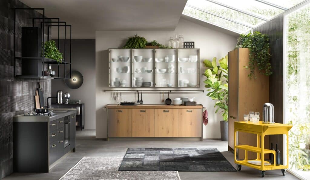 Modern kitchen with dark cabinets, wooden surfaces, glass-fronted cabinets, and various plants, featuring a bright yellow rolling cart with glassware.