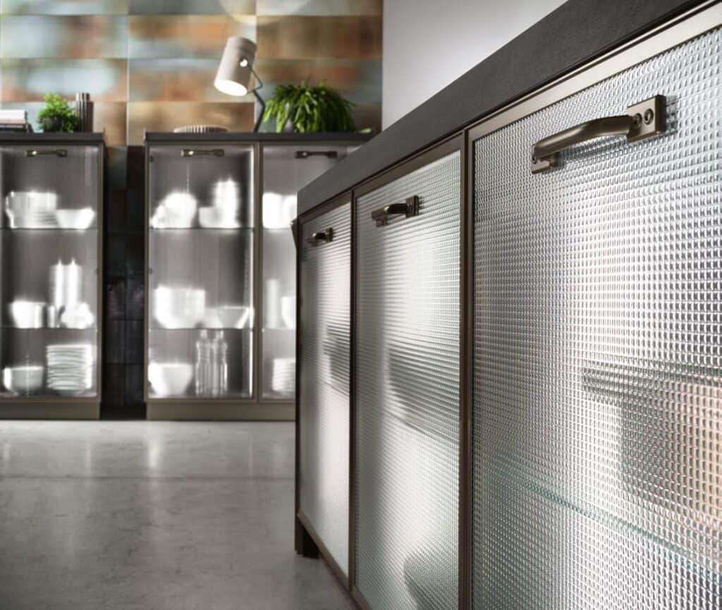 Textured glass cabinet doors with metal handles in a modern kitchen setting.