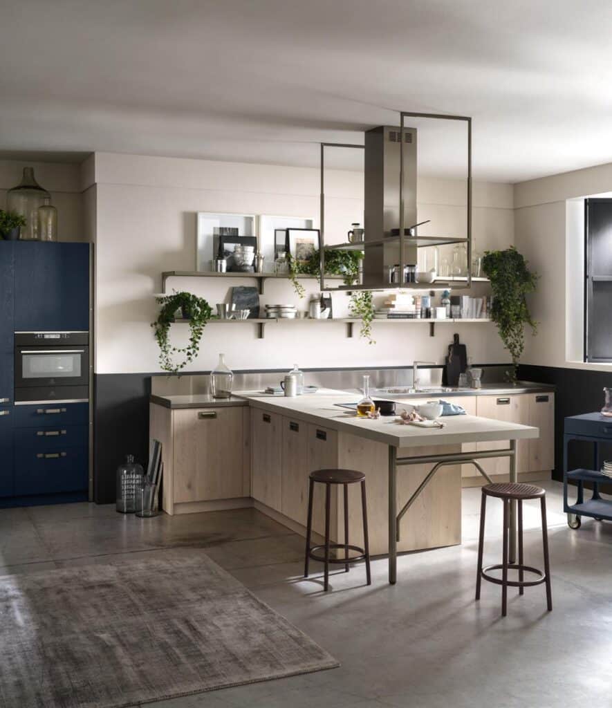Modern kitchen with wooden cabinets, an island with white countertop and bar stools, open shelves with plants and decor, and stainless steel appliances.