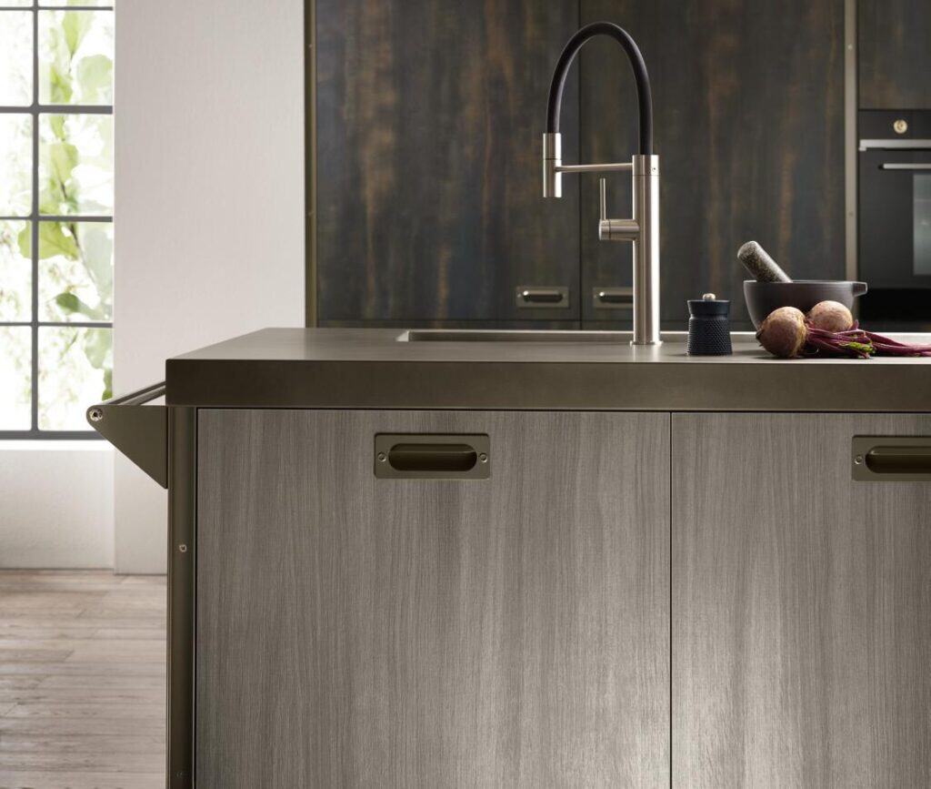 Modern kitchen island with a sleek metal finish, featuring a black and silver faucet, a bowl with beets, and a mortar and pestle on the countertop.