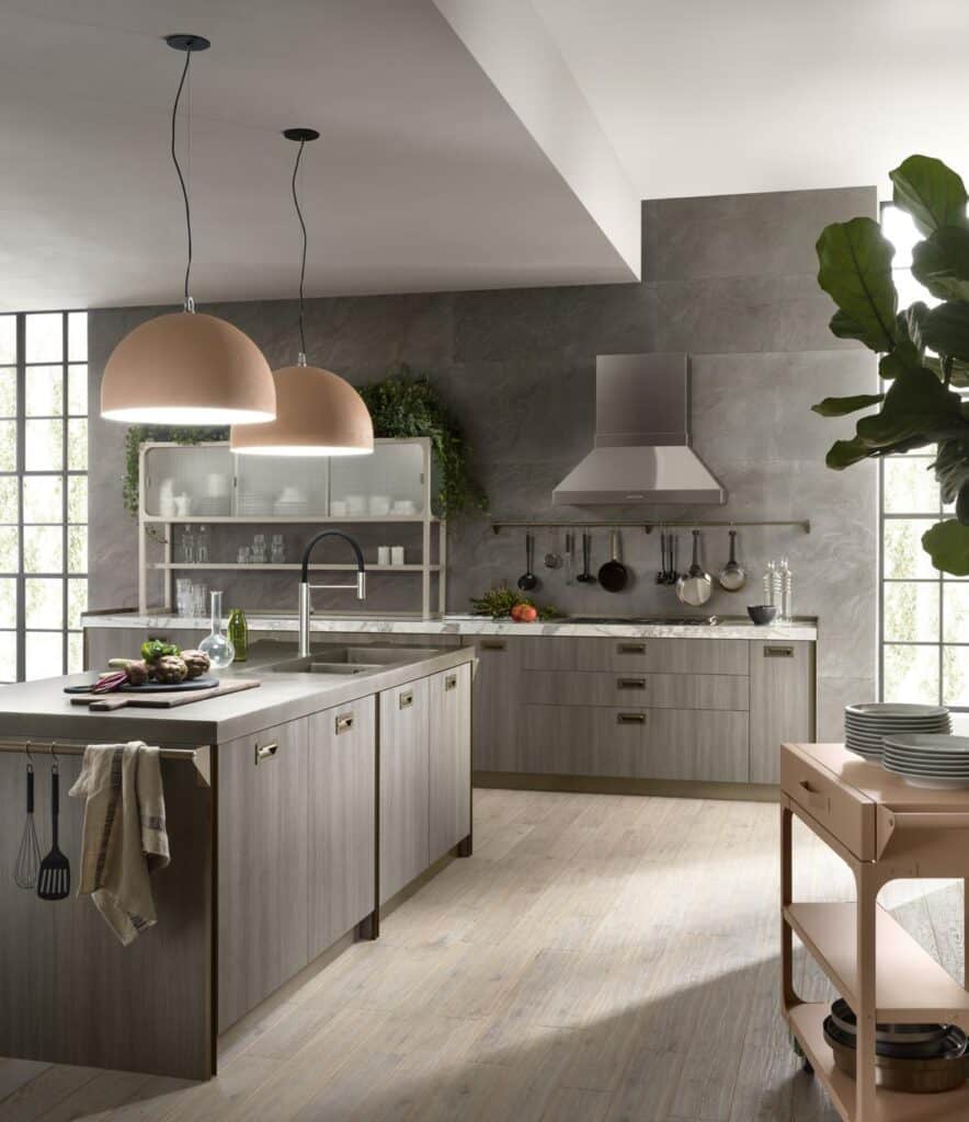 Modern kitchen with gray cabinets, a central island, hanging lights, potted plant, and utensils on a rack.