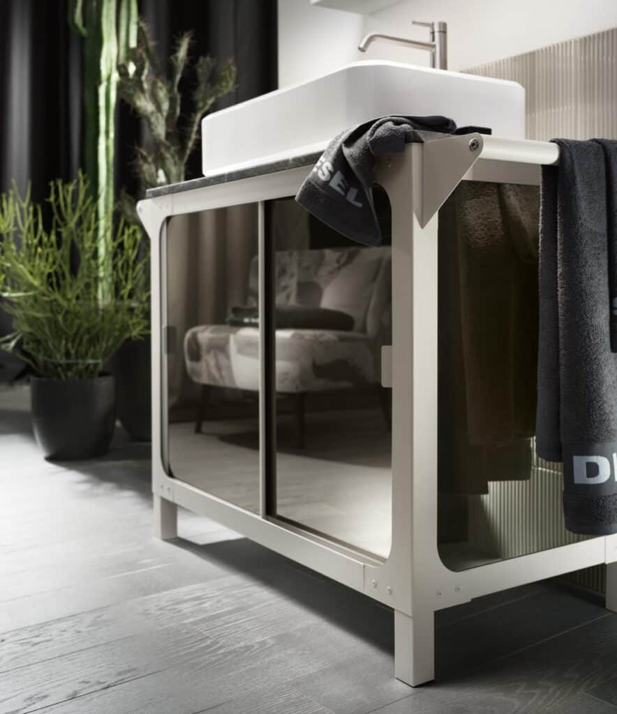 Modern bathroom vanity with a white basin, towels draped over the side, and potted plants nearby.