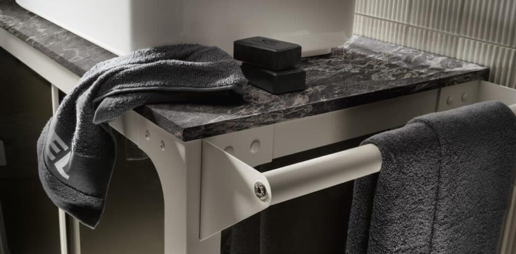 Marble countertop with a white sink, dark towels, and two black soap bars.