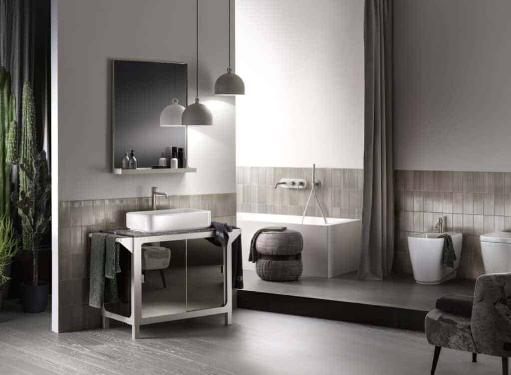 Modern bathroom with a sink, mirror, pendant lights, bathtub, and cacti in the corner.
