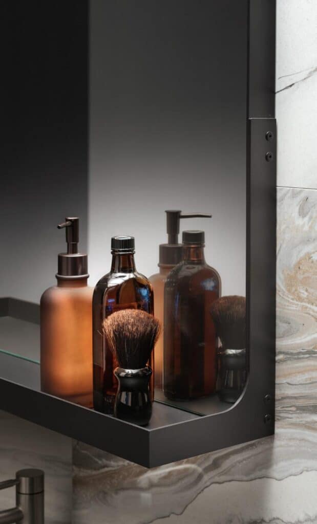 Bottles and a shaving brush on a bathroom shelf reflected in a mirror with a marbled wall background.