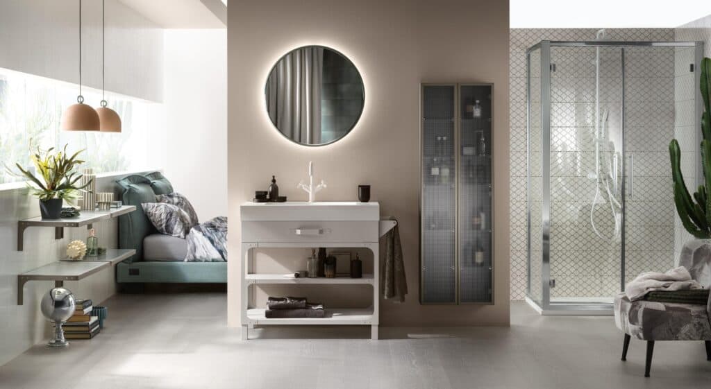 Modern bathroom and bedroom interior with a large round mirror above a white sink, shelving with decor, glass shower enclosure, and plant accents.