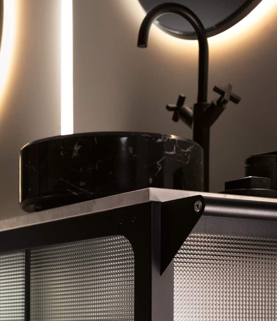 Modern bathroom vanity with a black marble sink and matte black faucet, illuminated by soft lighting.
