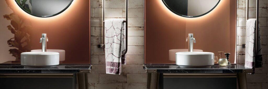Modern bathroom with two round mirrors, illuminated back panels, and vessel sinks on black countertops.