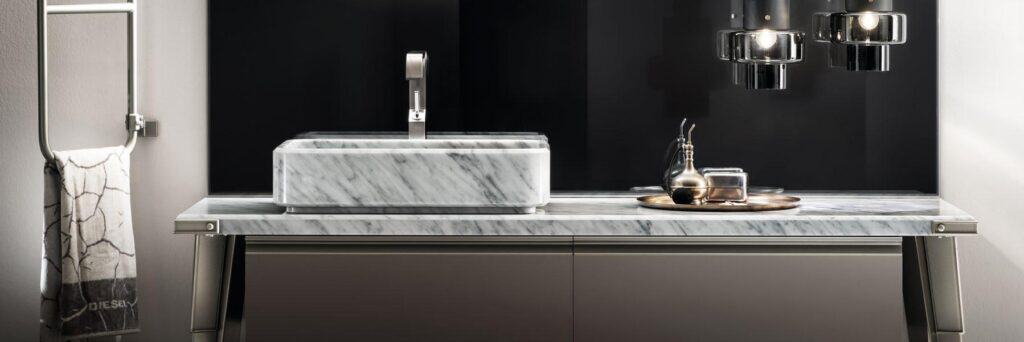 Modern bathroom with a marble countertop and sink, black pendant lights, and a towel on a metal rack.