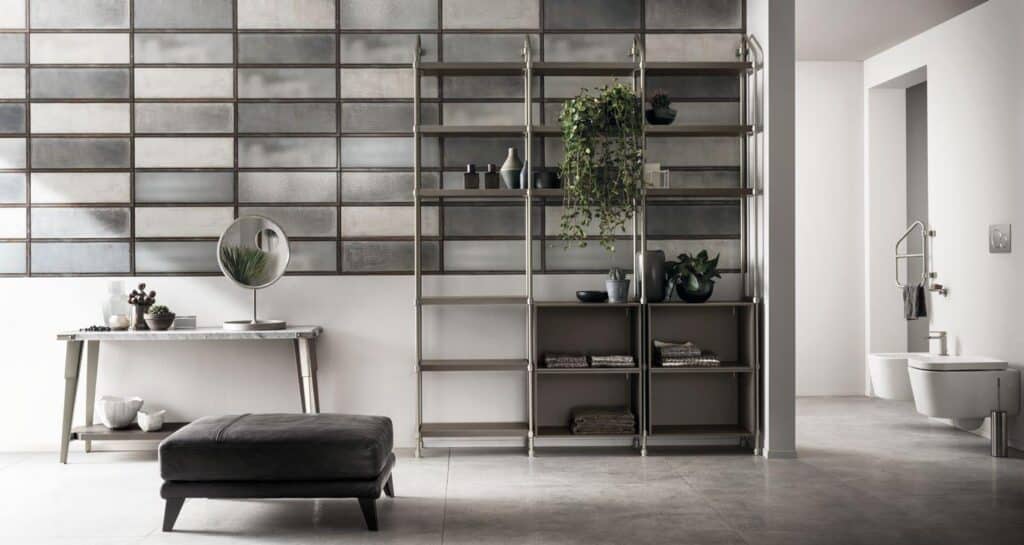 Modern bathroom with a tiled wall, open shelving with plants and decor, a console table with a mirror, a black ottoman, and a wall-mounted toilet.