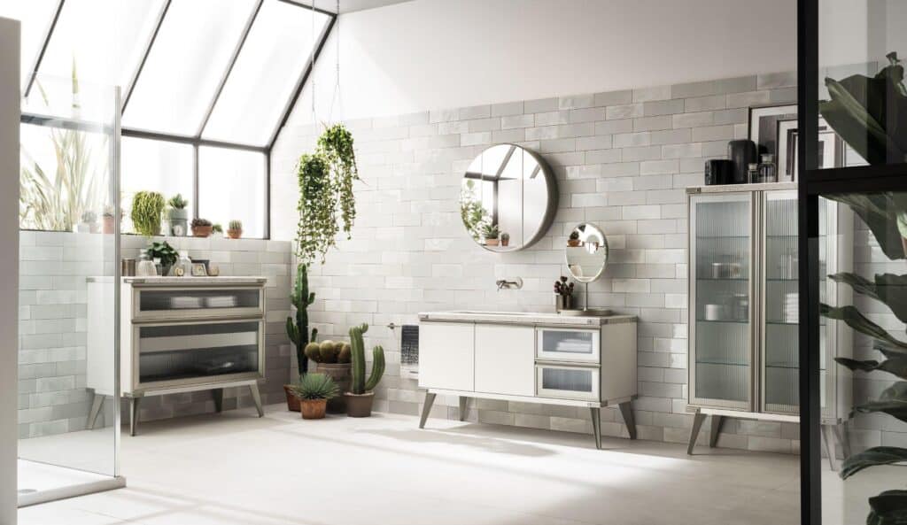 A modern bathroom with a skylight, featuring white tiles, a round mirror, a white cabinet with glass doors, and various potted plants including cacti.