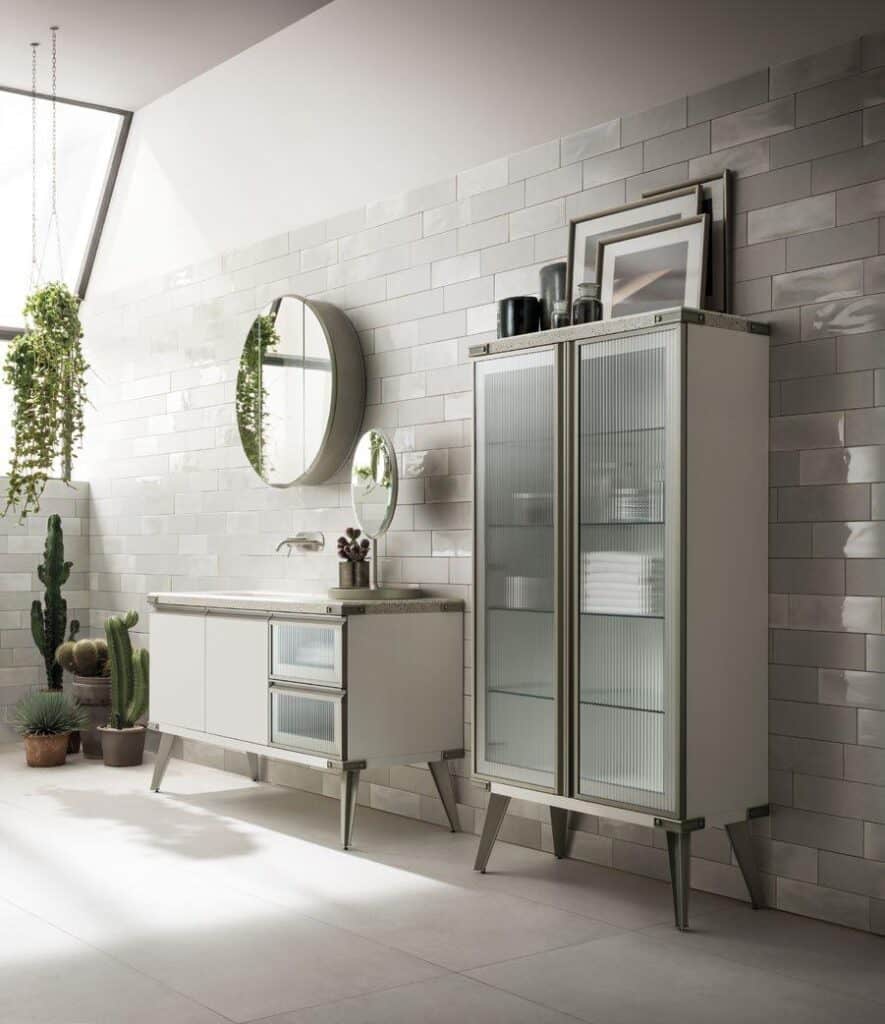 Modern bathroom interior with white tiled walls, a large mirror above a sink cabinet, a tall glass cabinet, and several potted plants, including cacti, placed on the floor.