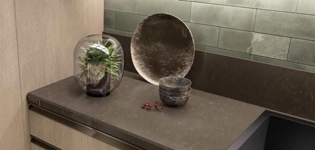 Modern kitchen countertop with a plant in a glass container, a decorative plate, stacked bowls, and small red berries.