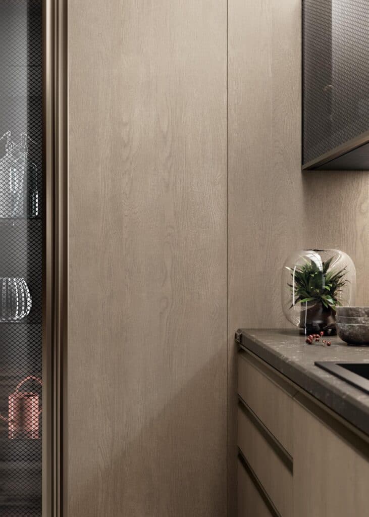 A modern kitchen interior with wooden cabinets, a marble countertop, and a potted plant in a glass cloche.
