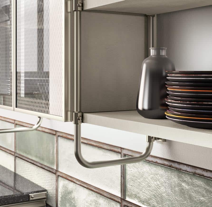 Kitchen shelf with a stack of plates and a dark vase, beside a mesh cabinet and metal bar, with glass tiled backsplash.