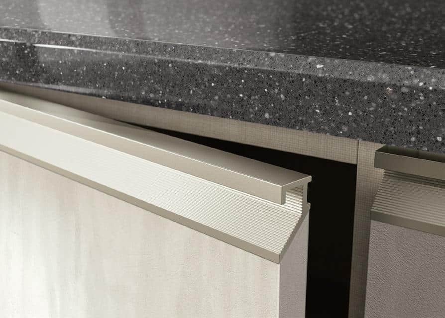 A close-up of a dark speckled countertop with a partially open cabinet below.