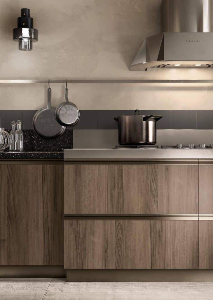 Modern kitchen with wooden cabinets, a black speckled countertop, hanging pans, a stainless steel pot on the stove, and a metallic vent hood.