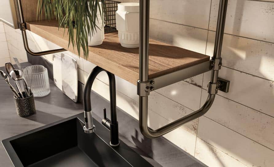 A modern kitchen sink area featuring a black faucet, a wooden shelf with plants, and utensil holders, set against a tiled backsplash.